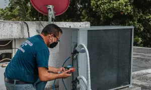 Technik sprawdza czujnik ciśnienia klimatyzacji, podłączając manometry do jednostki zewnętrznej.