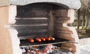Prosty murowany grill z cegły, na którym pieką się kiełbaski nad żarem.