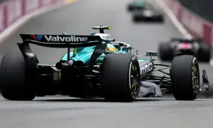 Un coche Aston Martin F1 verde compite en la pista, con otros coches borrosos detrás.