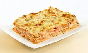 Une part généreuse de lasagne au saumon, avec ses couches de pâtes, de poisson rose et de fromage gratiné, prête à être dégustée.