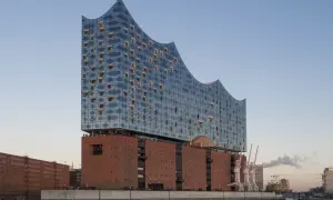 Elbphilharmonie Hamburg mit Glasfassade und Backsteinsockel am Wasser.
