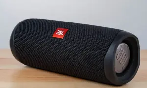 Czarny głośnik JBL na drewnianym blacie. Dowiedz się, jak podłączyć głośnik JBL do komputera przez USB, aby cieszyć się lepszym dźwiękiem.