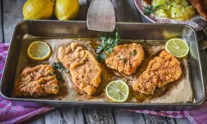 Vier saftige putenschnitzel im Ofen gebacken, garniert mit frischer Petersilie und Zitronenspalten.