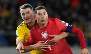 Robert Lewandowski, kapitan Polski, w czerwonej koszulce z orłem, walczy o piłkę z przeciwnikiem.