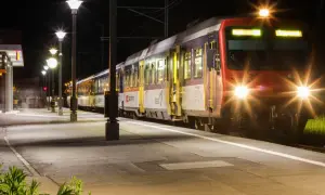 Ein Zug mit roten und blauen Waggons steht nachts am Bahnsteig. Die Scheinwerfer leuchten hell. Ein perfekter Start für eine Reise mit Interrail Italien.