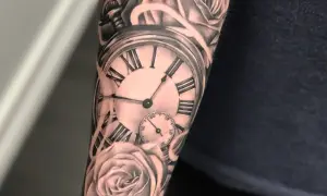 Tatuaż na ramieniu przedstawia kieszonkowy zegar z rzymskimi cyframi i róże. Symbolizuje, że tatuaż czas przemija.