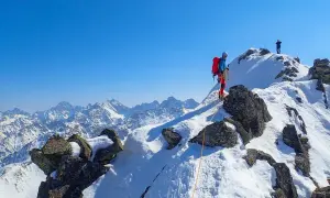 Wspinaczka na Orlą Perć zimą. Dwóch alpinistów na ośnieżonym szczycie, jeden z nich asekurowany liną.