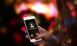 Dłoń trzyma smartfon Samsung z ekranem pokazującym przychodzące połączenie od nieznanego numeru. Chcesz wiedzieć, jak wyłączyć numer prywatny Samsung?