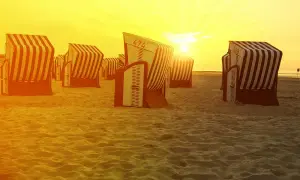Zachód słońca nad plażą na Morzu Północnym w Niemczech. Puste kosze plażowe czekają na gości.