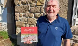 Un homme souriant tient un livre sur l'histoire du breton écrit. Son nom de famille breton est Favreau.