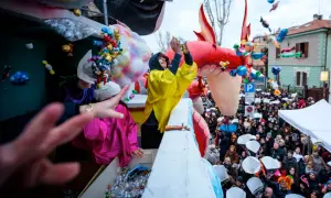 Carnevale a Fano: dolciumi volano da un carro allegorico tra la folla festante.