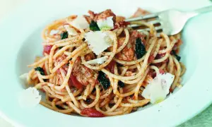En portion tonfisksallad med pasta, toppad med parmesan och örter. En gaffel vilar i tallriken.