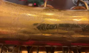 Złoty saksofon C.G. Conn z wygrawerowanym napisem i ornamentami.