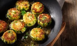 Zucchini puffer in einer Pfanne braten. Goldbraun und knusprig, mit frischer Petersilie garniert.