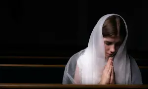 Dziewczyna w białym welonie, z dłońmi złożonymi do modlitwy, szuka spokoju i pogłębia swoją więź z Bogiem poprzez codzienną medytację.