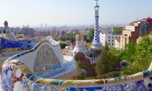 Bunte Mosaikbänke und Gaudís Märchenhäuser im Park Güell, eine der berühmtesten Barcelona Attraktionen, mit Blick auf die Stadt.