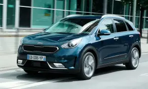 Ciemnoniebieski Kia Niro jedzie ulicą obok nowoczesnego budynku.