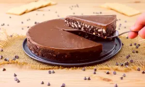 Una fetta di golosa torta fredda al cioccolato, con biscotti sbriciolati e una lucida glassa, viene sollevata da una paletta.