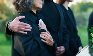 Odprawa pośmiertna: bliscy w żałobie, objęci ramieniem, trzymają chusteczkę.