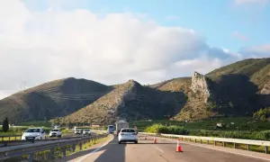 Podróż samochodem do Hiszpanii. Autostrada wśród zielonych wzgórz, słońce i chmury na niebie.