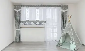 Jak dobrac firanki do okna? Szare zasłony w gwiazdki i białe firanki tworzą przytulną atmosferę. Obok namiot tipi.