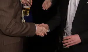 Dwóch mężczyzn w garniturach ściska sobie dłonie, trzymając piwo. Czy to początek udanej transakcji, czy może ukryte wady oświadczenia woli?