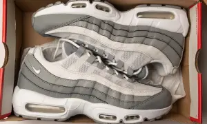 Szare i białe buty sportowe Nike Air Max 95, znane jako ermaksy, leżą w kartonowym pudełku.