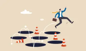 Un homme d'affaires saute par-dessus des trous, évitant les cônes de signalisation. Une métaphore visuelle pour surmonter les obstacles, comme un exemple d'arrêt de travail.