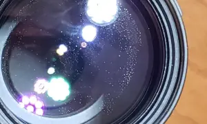 Widoczne na soczewce drobne kropki i kolorowe refleksy, przypominające aberrację chromatyczną, tworzą na czarnym tle ciekawe wzory.
