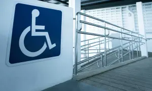 Segnale di accessibilità per disabili accanto a una rampa con corrimano, a norma con la legge 104 per l'abbattimento barriere architettoniche.