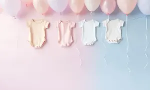 Urocze body dla niemowlaka wiszące na wstążkach pod balonami. Idealne, by pomyśleć, co napisać z okazji narodzin dziecka.