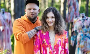 Para pozuje wśród kolorowych sukienek. Mężczyzna w pomarańczowej bluzie, kobieta w marynarce. Naoko - co to za firma?