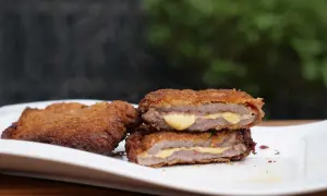 Zwei dampfende Cordon Bleu auf einem Teller, das Fleisch ist saftig, der Käse schmilzt.