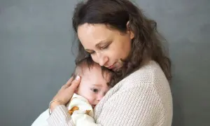 Kobieta tuli dziecko na tle szarej ściany.