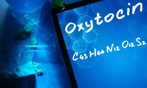 Badania nad oksytocyną u mężczyzn. Na ekranie tabletu widnieje nazwa "Oxytocin" i jej wzór chemiczny. Wokół leżą tabletki, proszek i probówki.