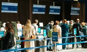 Kolejka do odprawy bagażowej. Na ekranach widnieje napis "BAGGAGE DROP-OFF", ale nie ma żadnego "no show".