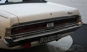 Vit cougar bil med kromdetaljer och en ikonisk grill. En klassiker som väcker nostalgi.