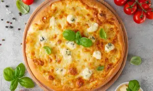 Une délicieuse pizza 4 fromages, dorée et garnie de basilic frais, prête à être dégustée.