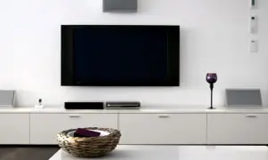 Nowoczesny salon z dużym telewizorem na ścianie, białymi meblami i dekoracjami.