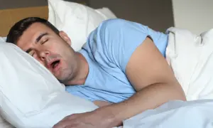 Mężczyzna śpi z otwartymi ustami, co może sugerować ślinienie się w nocy.