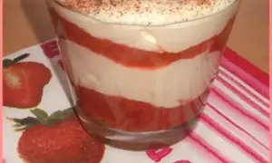 Un délicieux tiramisu rhubarbe fraise, superposé en couches dans un verre, garni de fraises et de cacao.
