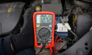 Multimetr pokazuje 12.72V, co jest kluczowe, jak sprawdzić akumulator. Pomiar napięcia baterii w samochodzie.