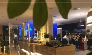Elegancki sylwester w hotelu. Goście siedzą przy stołach, w tle bufet z przekąskami i świąteczne dekoracje.