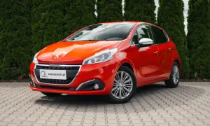 Czerwony Peugeot 208 z błyszczącymi światłami, idealny na egzamin na prawo jazdy.