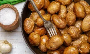 Pommes de terre grenaille dorées et croustillantes, tout juste sorties de l'airfryer. Une fourchette est plantée dans ce délice salé.