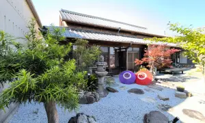 Tradycyjny dom na wyspie Japonii z Kagawa, z kamiennym ogrodem, parasolami i jesiennym drzewem klonowym.