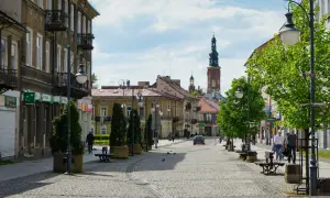 Ulica w Radomiu z kamienicami, wieżą kościelną i zielenią.