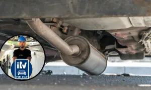 Inspección del tubo de escape de un coche. Un mecánico con casco azul supervisa la revisión.
