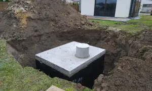 Zbiornik na deszczówkę w wykopie, gotowy do podłączenia do rynny.