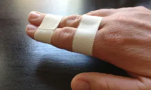 Zwei Finger sind mit Pflaster verbunden, um sie zu stabilisieren. Das Finger tapen hilft bei der Heilung.